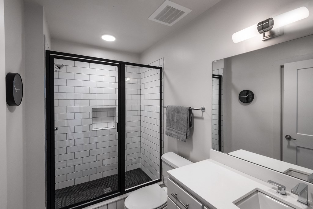 a bathroom with a white sink and toilet and a shower with a glass door